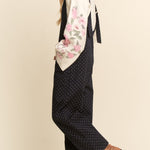 Woman wearing a floral top and polka dot pants with a beige background