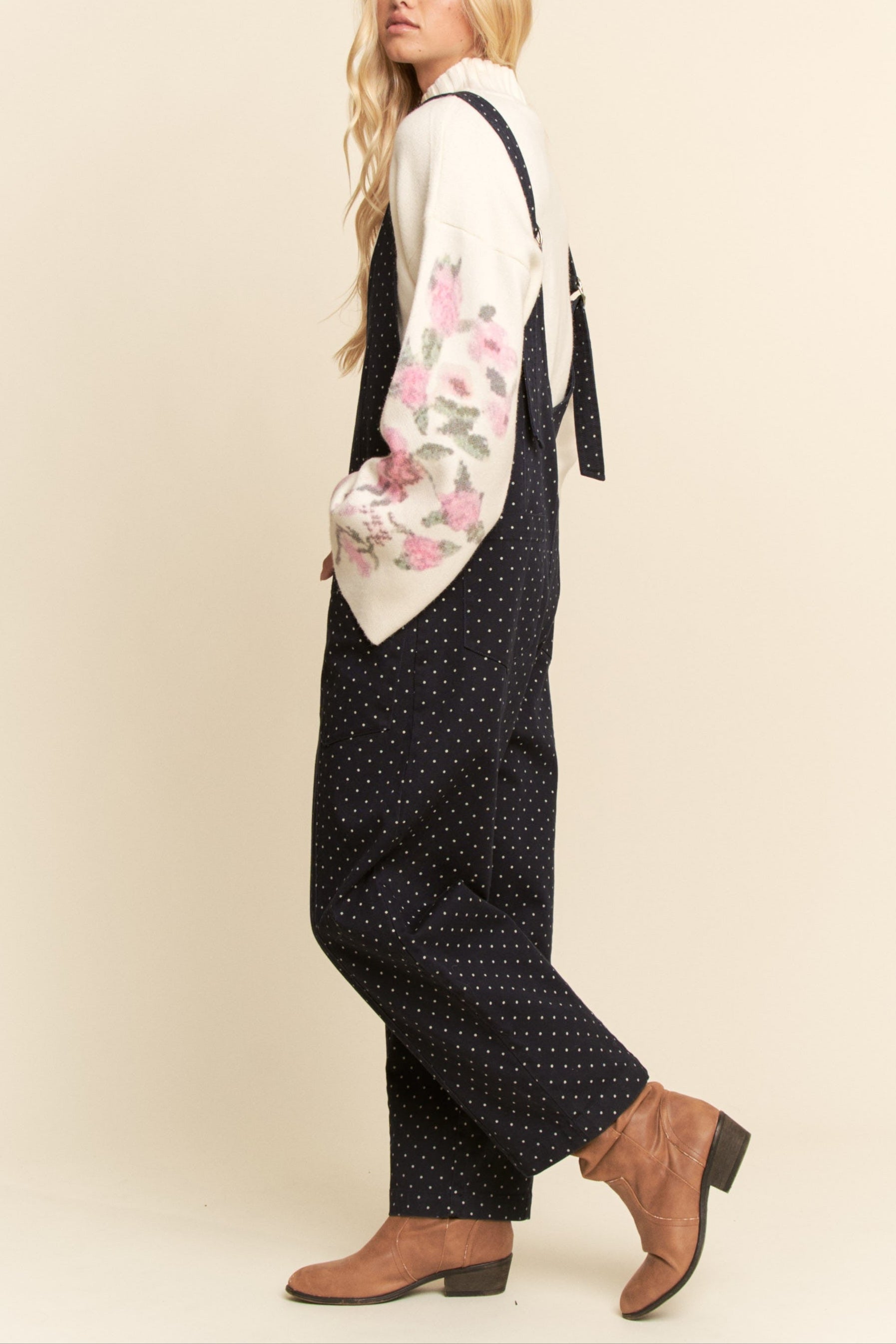 Woman wearing a floral top and polka dot pants with a beige background