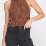 Woman wearing a brown knitted halter top and black jeans on a white background