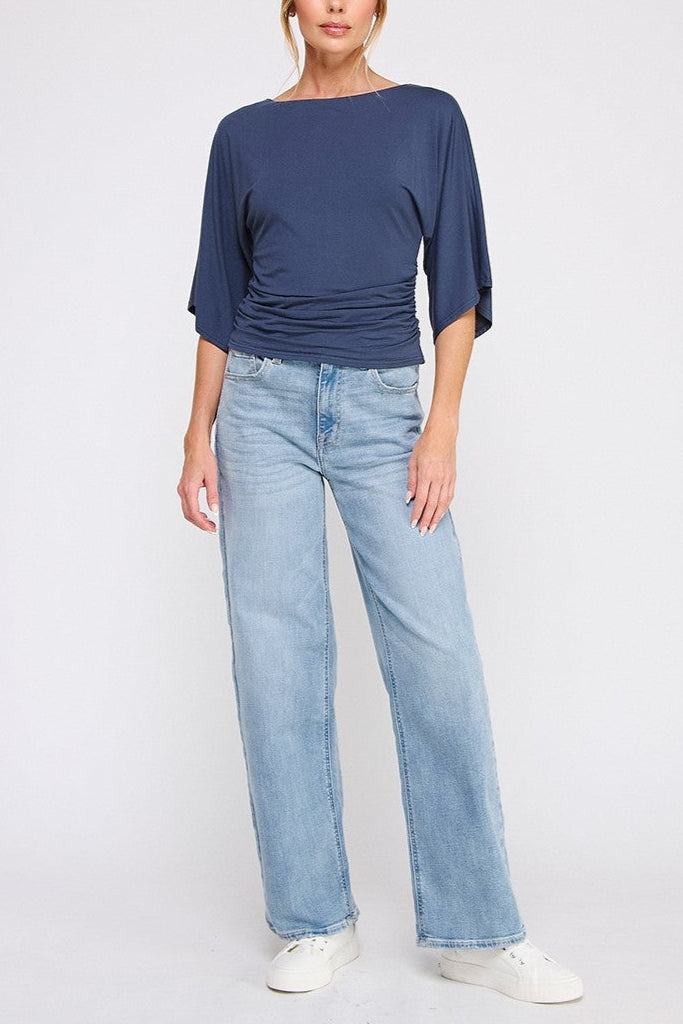 Woman wearing a navy blue top and light blue jeans on a white background