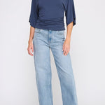 Woman wearing a navy blue top and light blue jeans on a white background