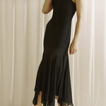 Woman wearing a black dress against a white curtain background