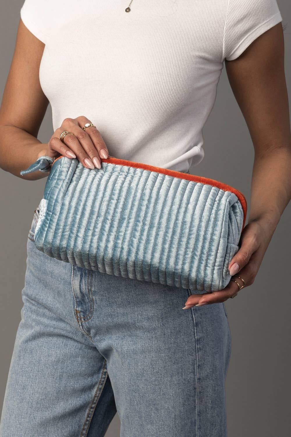 Juniper Velvet Ribbed Pouch in light blue and orange, held