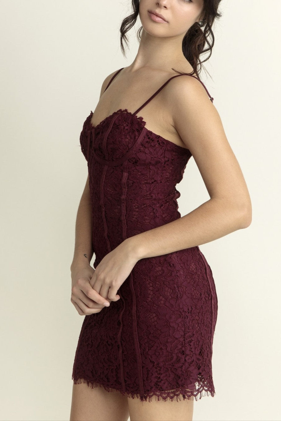 Woman wearing a burgundy lace dress against a plain background
