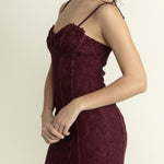 Woman wearing a burgundy lace dress against a plain background