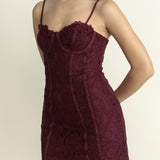 Woman wearing a burgundy lace dress against a plain background