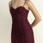 Woman wearing a burgundy lace dress against a plain background