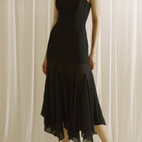Woman wearing a black slip dress against a white curtain background