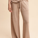 Person wearing beige ribbed pants and top on a beige background