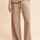 Person wearing beige ribbed pants and top on a beige background