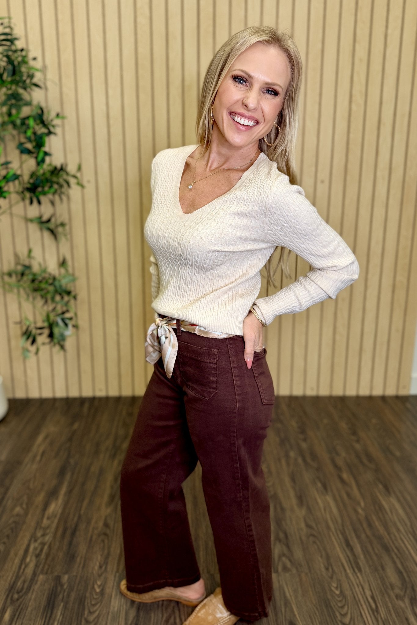 The Lila Cable Knit V-Neck Sweater in Sandshell with brown wide leg pants, front view