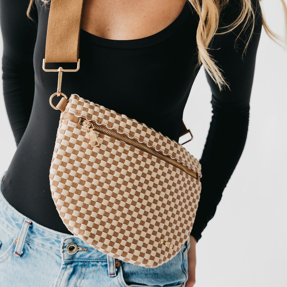 Person wearing a checkered crossbody bag with a plain background